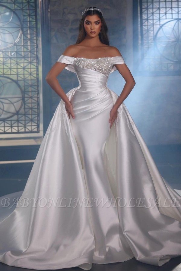 Блестящее белое свадебное платье силуэта «русалка» с открытыми плечами и верхней юбкой